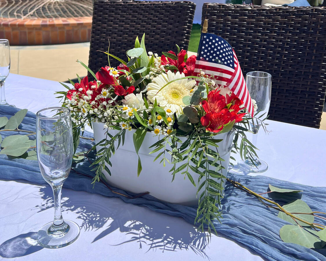 Red and white floral centerpiece with American flag accent for outdoor patriotic baby shower table design